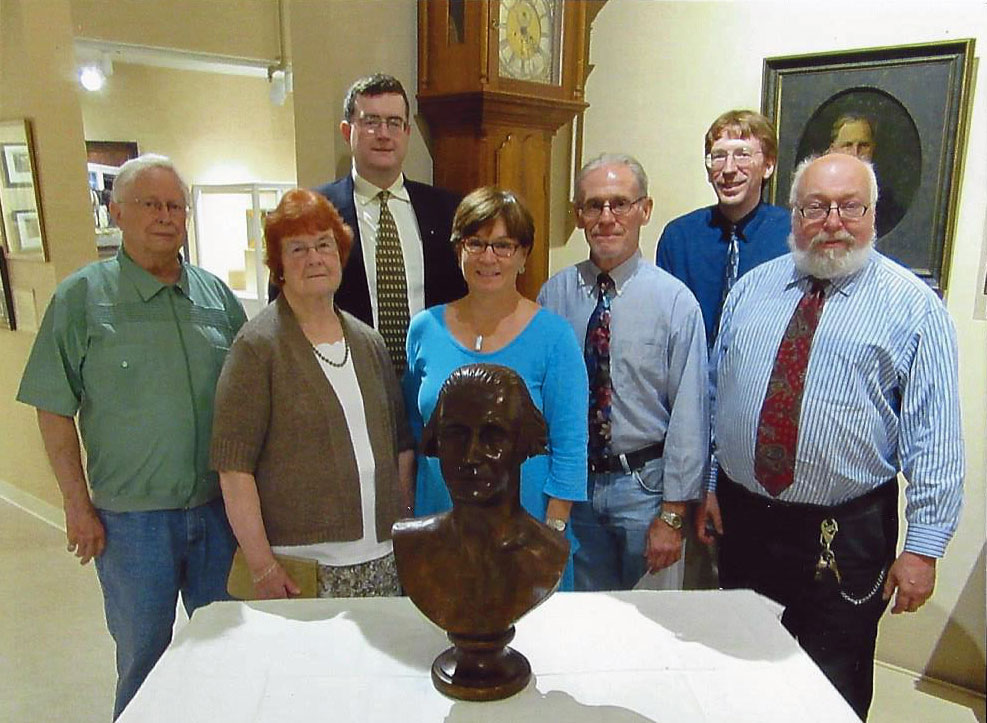 Museum Board member Eiderson Dean, widow of the carver Jane Landon, son of the carver Ben Landon, donor Susan G.S. Anderson, donor Dan Llewellyn, Curator Scott Sagar, and Museum Director Gary Parks.